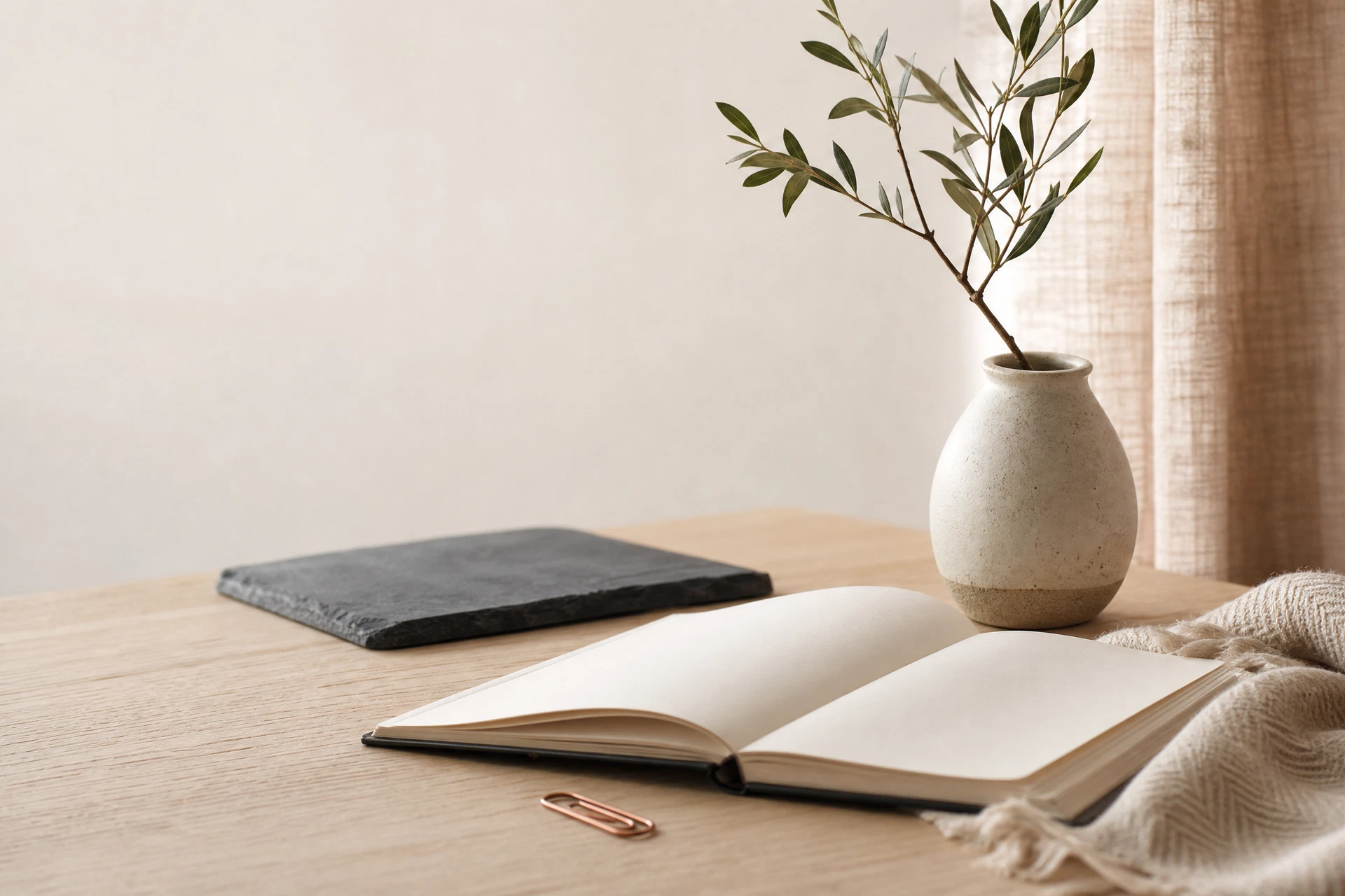 A quiet light-filled room with an oak desk and a small branch